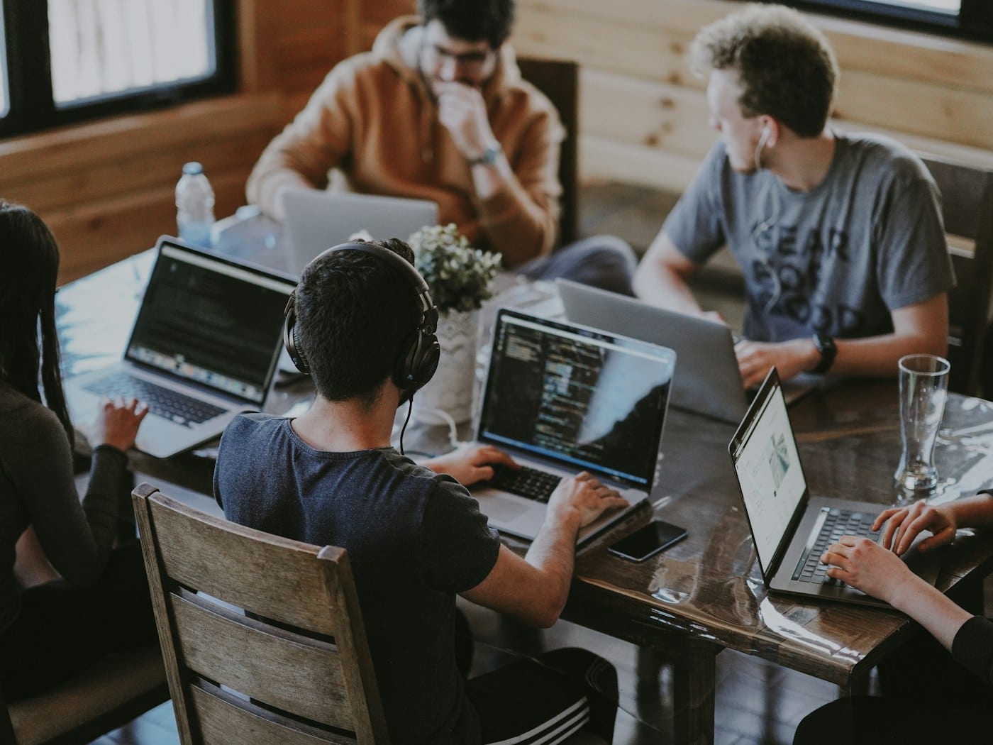 Team members collaborating over laptops at a shared desk